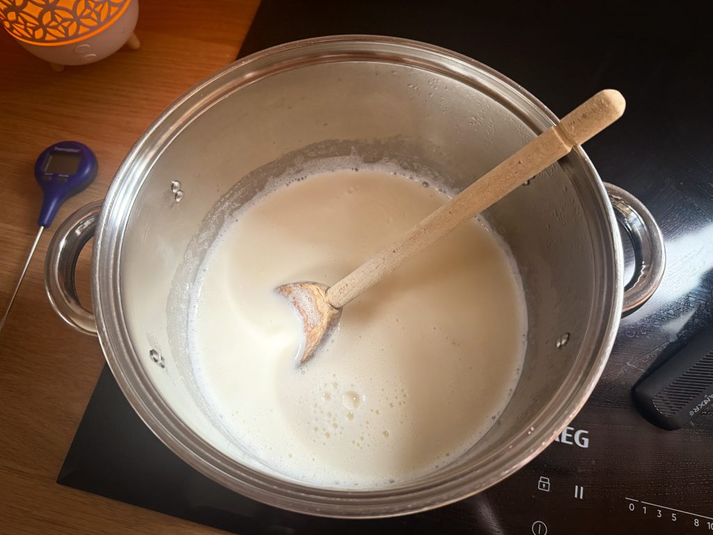 Milk heating up on stove. How to make homemade yoghurt by A Hopeful Home blog.