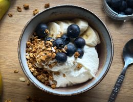 Header image how to make homemade yoghurt by the A Hopeful Home blog. The image shows a bowl of yoghurt with blueberries, granola, and banana on top.